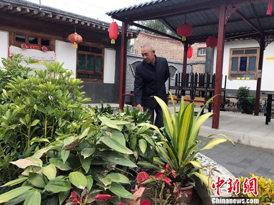 图为独石村村民张勤打理农家乐中的花卉。　艾庆龙 摄